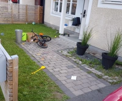 Förebild på husets entré innan altanbyggnation – stenlagd gång och gräsmatta utan uteplats.