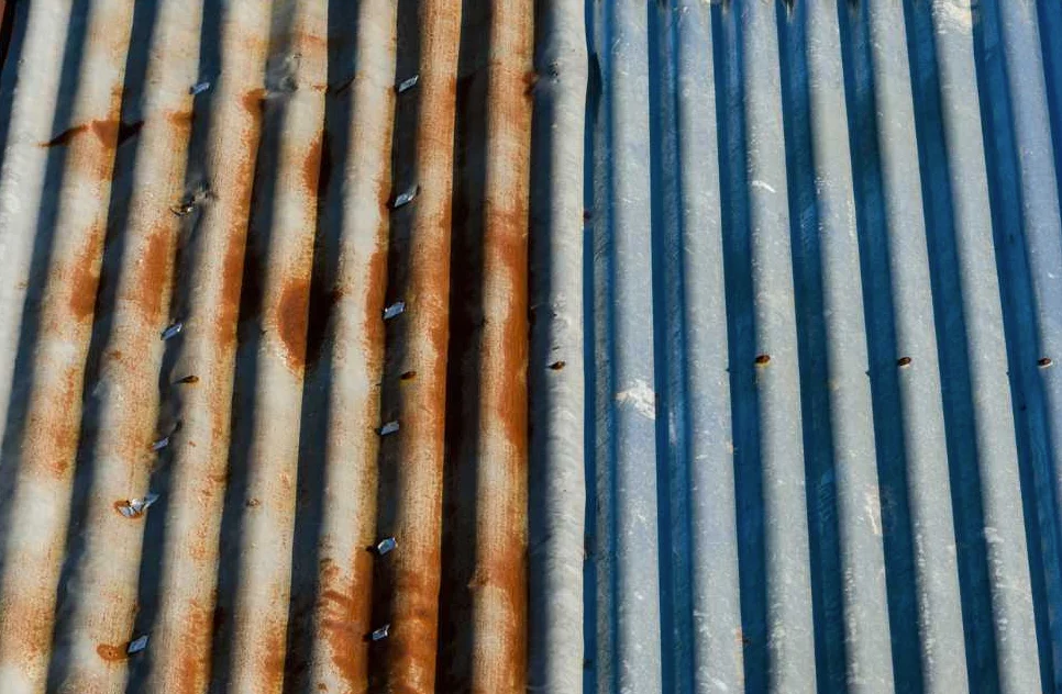 Jämförelse av ett plåttak som drabbats av korrosion brevid en del taket som inte har korrosion.